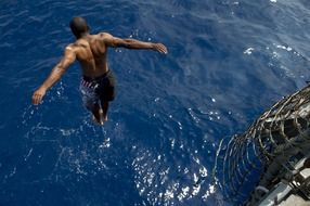 man jumping into the blue water