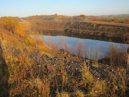 brown autumn grass grows along a natural quarry