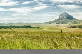green grassland and scenic rock at cloudy sky, south africa