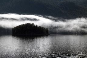 dark early foggy morning over the island on the lake