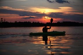 man in canoe at sunset on the river