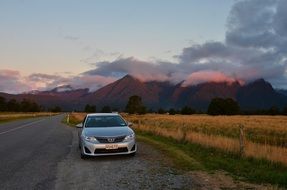 car on the road in new zealand during sunset