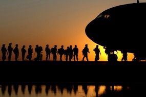 the soldiers at the plane against the backdrop of an orange sunset