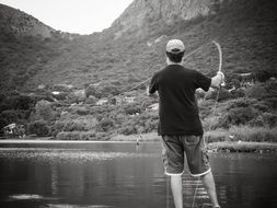 black and white photo of a fisherman on the lake