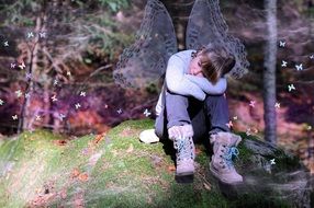Child sits on a green green hill among the colorful plants in the beautiful forest