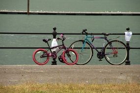 two bicycles parking at railings in front of water