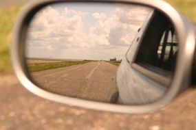 Beautiful back reflection of the road among the fields in the mirror