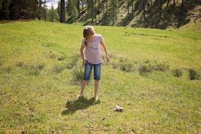 child girl stays on meadow on a sunny day