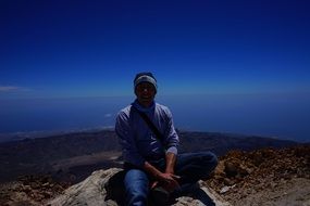 man sitting on rock sea view