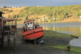 old red boat on scenic coast, chile, chiloé
