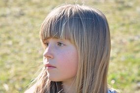 photo of a pensive girl with blond hair on a blurred background