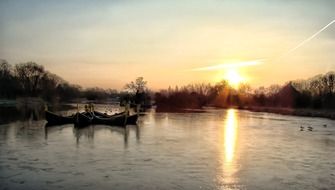 landscape of sailing boats on lake at golden sunset with trees silhouette