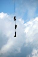 people are hanging on a rope in the sky