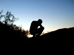 man squatting in the dark