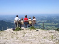 back view of family resting on bench at alpine mountain