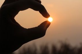 view of sunset sun between fingers