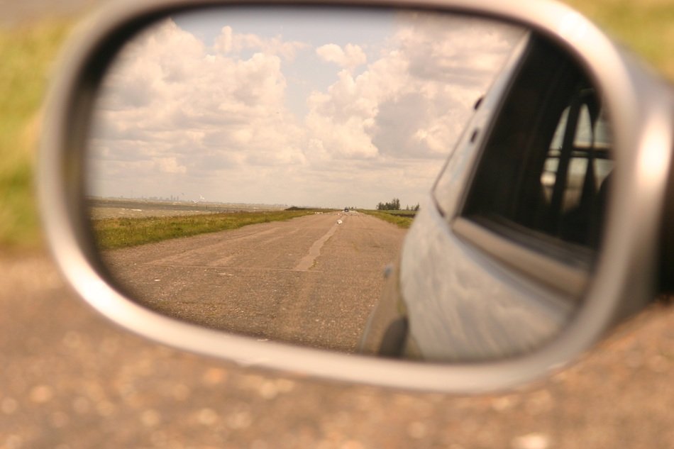 Beautiful back reflection of the road among the fields in the mirror