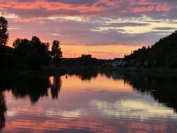 Beautiful and colorful landscape with the sunset with its reflection in the water among the plants