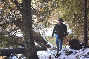 man in a hat walking in a snowy forest