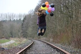 girl with balloons jumps on the train tracks
