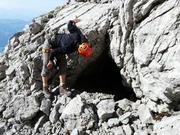climber looking at cave entrance in rock on a sunny day