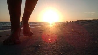 man's feet walking on the beach at sunset