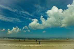 scenic row of white fluffy clouds in sky above beach