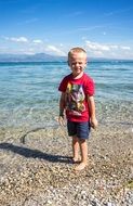 photo of happy blonde boy on lake garda shore