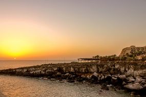 sunset on the horizon against a rocky shore
