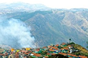 Upper landscape of a beautiful mountain village with red roofs and smoke in India