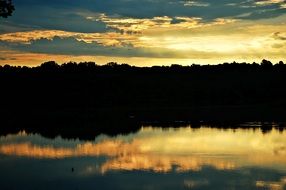 reflected forest and sky in a lake at dawn