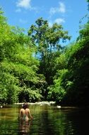 girl is swimming in a clean pond in summer