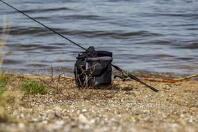 bag and fishing rod on the shore of the reservoir