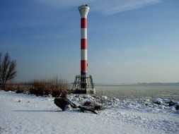 high lighthouse tower on river bank in winter