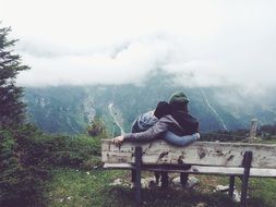 couple in love sitting on a bench and looking at the mountains