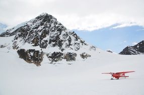 red plane on snow mountain in Alaska