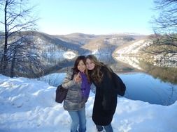 Beautiful landscape of snowy nature with colorful plants and women near the water in Croatia