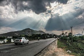 sun rays through clouds over an asphalt road