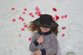 girl lying on the snow in rose petals