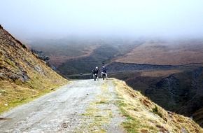 two motocross racers on mountain trail at colorful scenic landscape