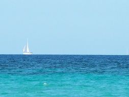 blue seascape with white sailing boat, italy, sardinia