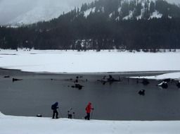 people wearing snowshoes at mountain lake