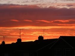 sunset over silhouettes of roofs