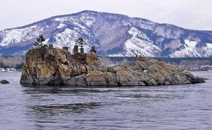 stone island in the middle of the river on a background of snowy mountain