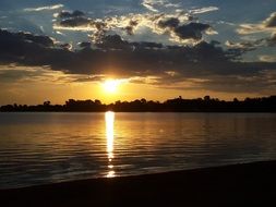 view from the beach to the bright sun at sunset