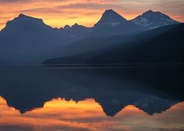 mountains and sunset sky reflection on calm water