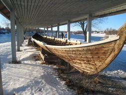 traditional long wooden boat beneath shed at winter, sweden