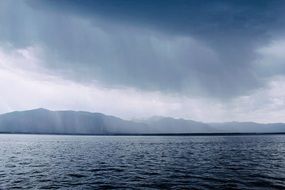 Beautiful rain from clouds above the water coast with cliffs