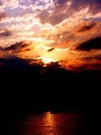 sunset behind dark clouds over the lake at dusk