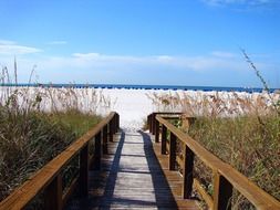 boardwalk to white sand beach at blue sea